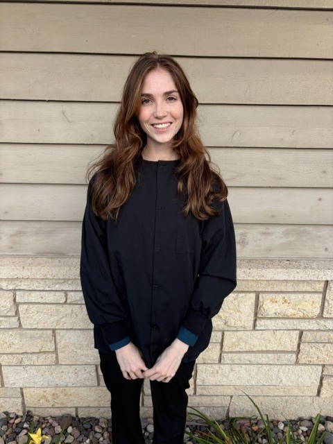 Emi, dental assistant, smiling outdoors in dark scrubs near the office